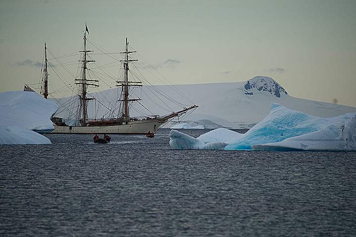 a ship sailing in the ocean near icebergs