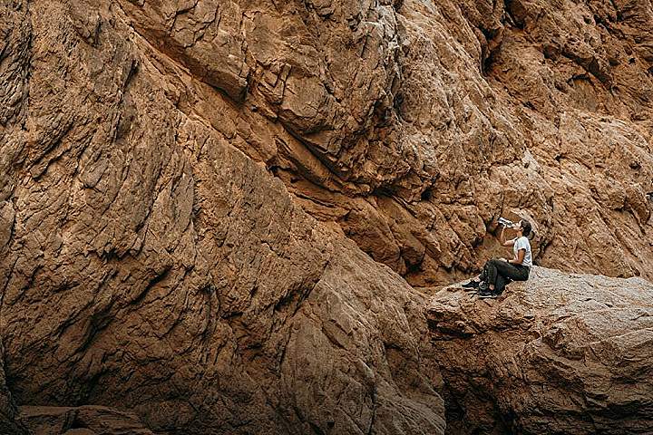 a woman sitting on top of a rock next to a cliff