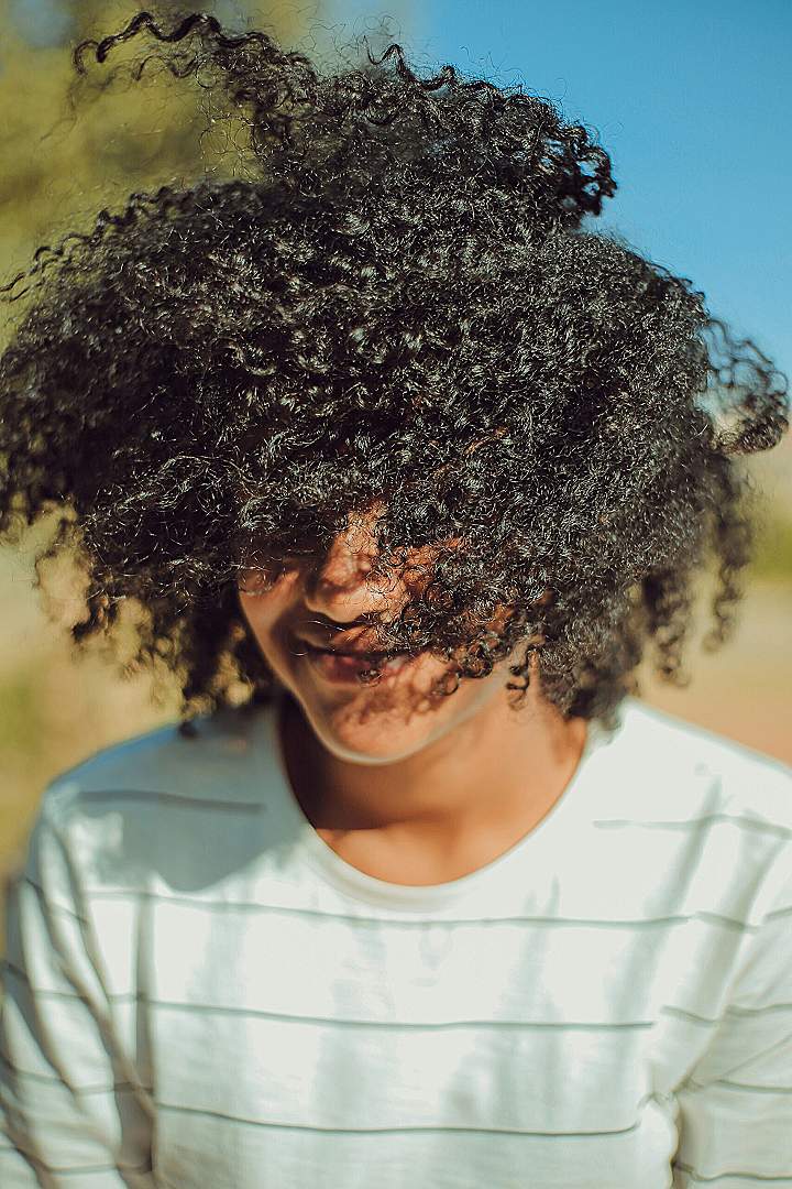 person wearing white crew-neck shirt with curly hair photo