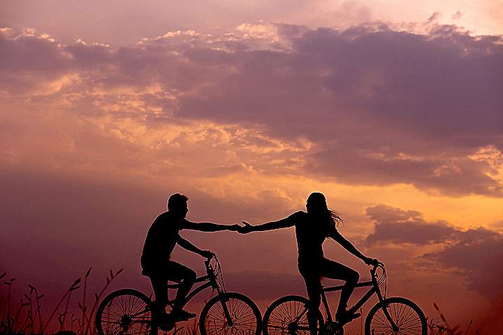 woman on bike reaching for man's hand behind her also on bike