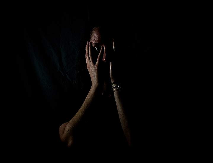 woman holding her face in dark room