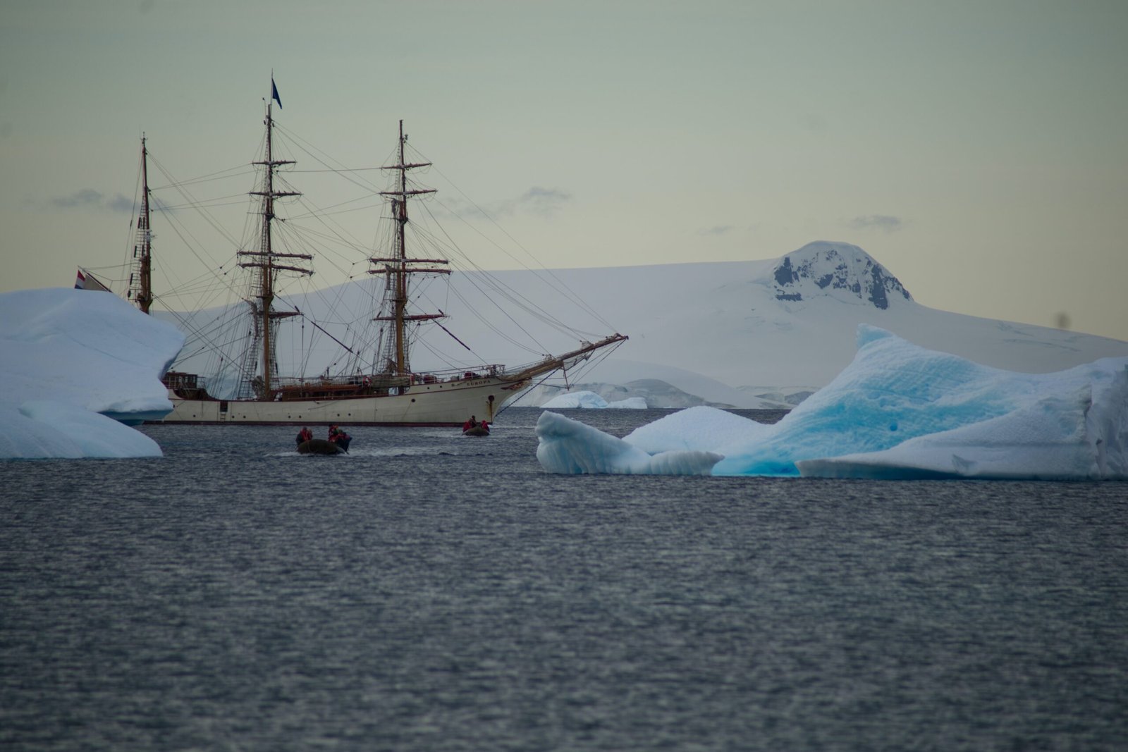 a ship sailing in the ocean near icebergs