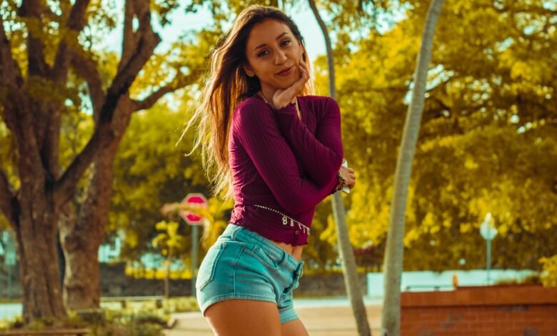 woman in purple long sleeve shirt and blue denim shorts standing on pathway during daytime